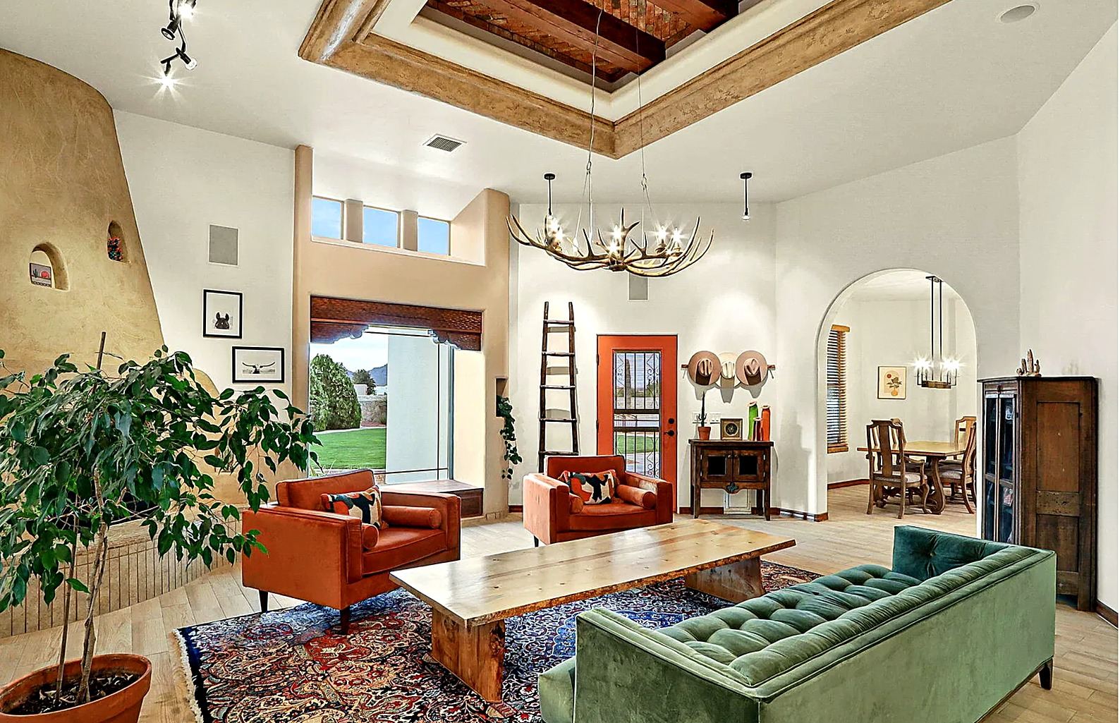 The Fox Den Court living room in Las Cruces, with a beamed ceiling, orange chairs, and a green sofa