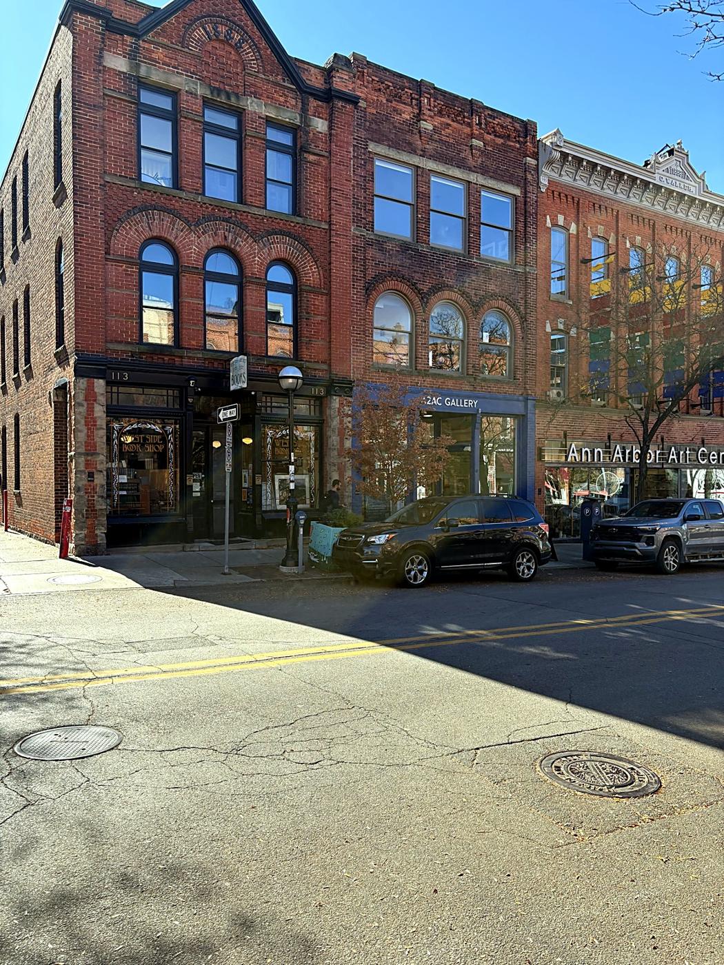 A row of brick storefronts downtown, with a bookshop and gallery