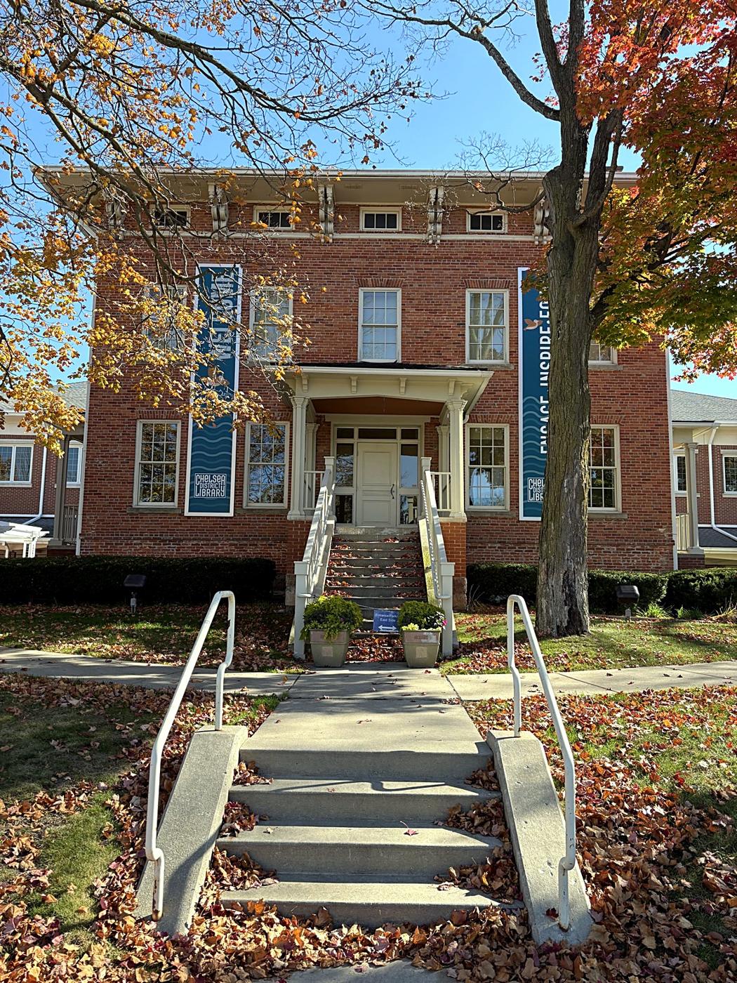The Chelsea District Library, a brick building framed by fall trees