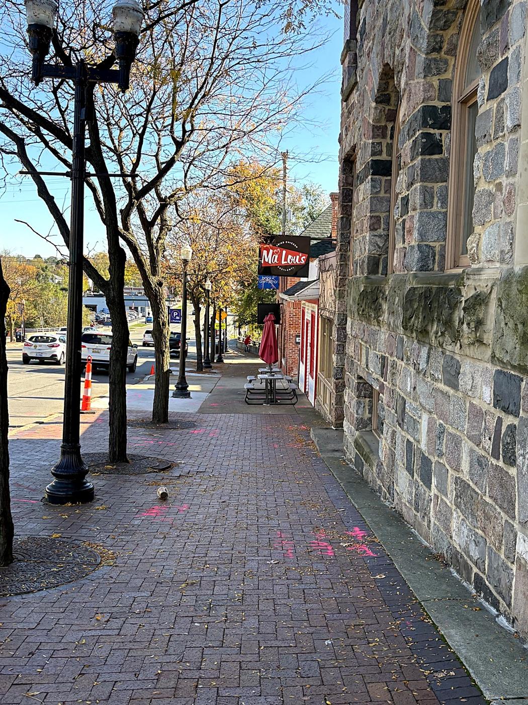 A brick sidewalk along Michigan Avenue beside an old stone church wall