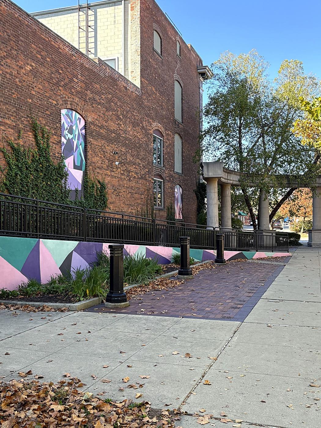 A geometric mural along a brick wall near Depot Town